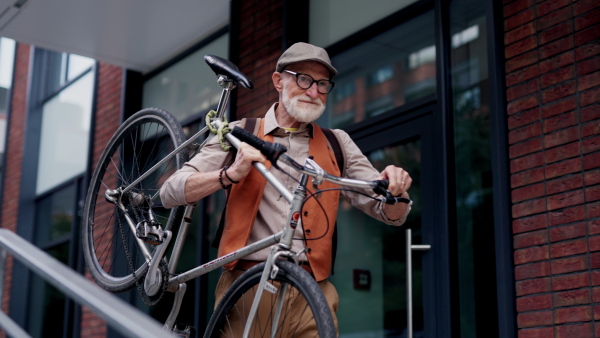 An elderly man, cyclist traveling through the city by bike, carrying bicycle on shoulder. Senior city commuter riding a bike.