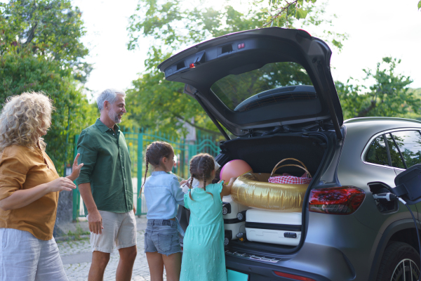 A fmily with little children loading car and waiting for charging car before going on holiday.