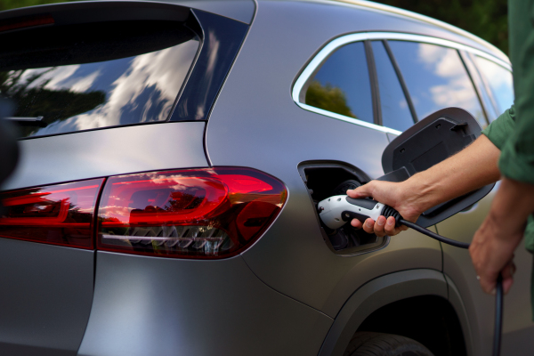 A man holding power supply cable at electric vehicle charging station, closeup