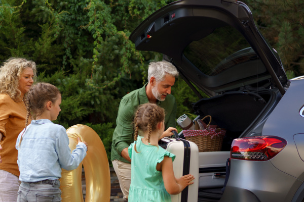 A fmily with little children loading car and waiting for charging car before going on holiday.