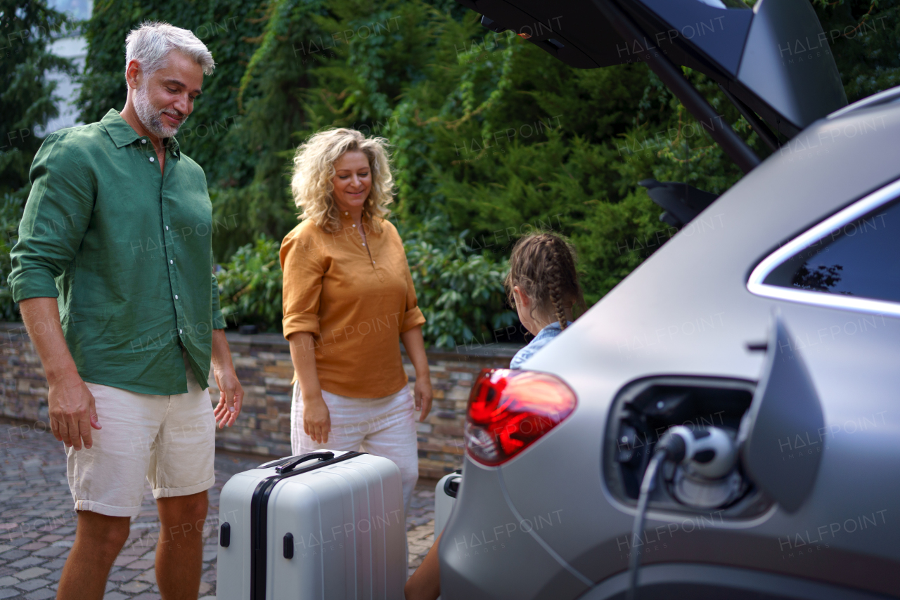 A fmily with little children loading car and waiting for charging car before going on holiday.