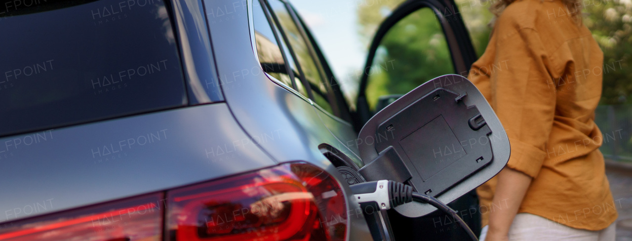 Woman waiting while her electric car charging, close-up.