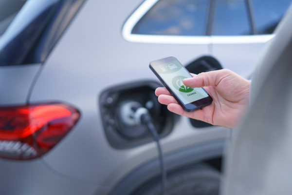 Man setting phone application for charging his electric car at a charging station, closeup.