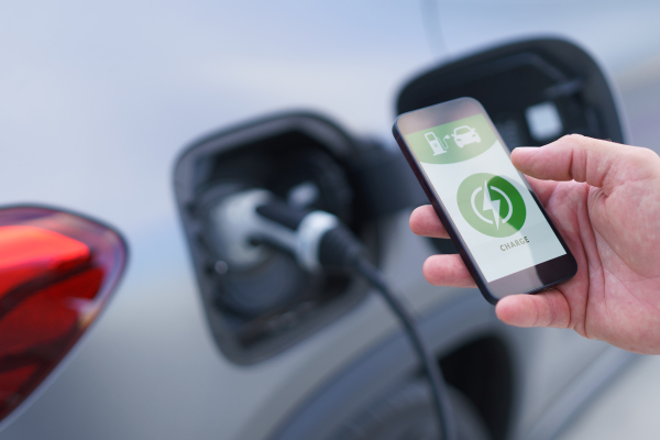 Man setting phone application for charging his electric car at a charging station, closeup.