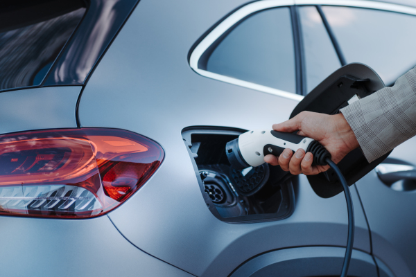 A man holding power supply cable at electric vehicle charging station, closeup