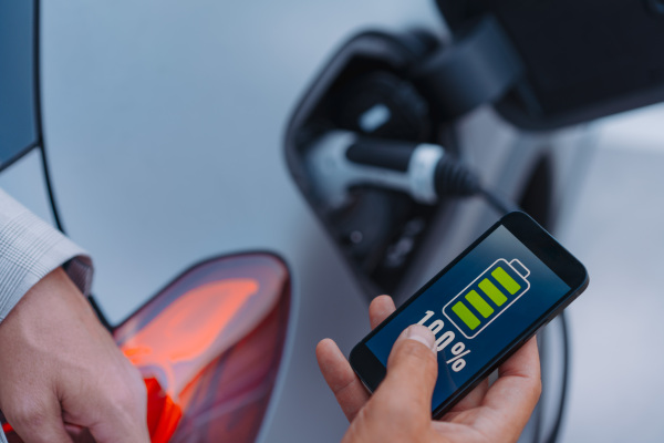 Man setting phone application for charging his electric car at a charging station, closeup.