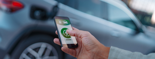 Man setting phone application for charging his electric car at a charging station, closeup.