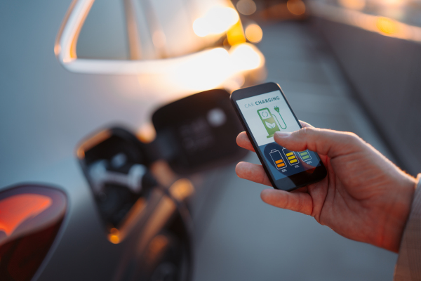 Man setting phone application for charging his electric car at a charging station, closeup.