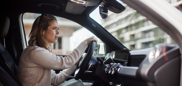 Upset woman driving her car in city.