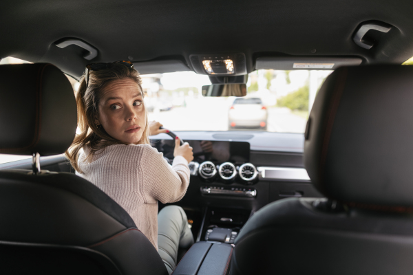 Happy woman driving her new electric car in a city.