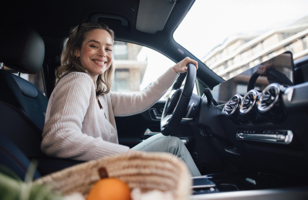 Happy woman driving her new electric car in a city.