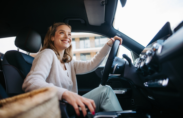 Happy woman driving her new electric car in a city.