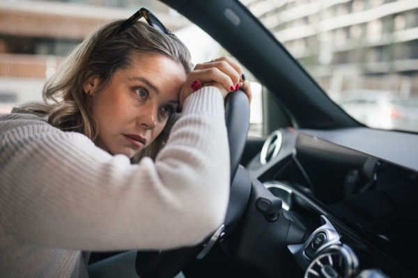 Upset woman driving her car in city.