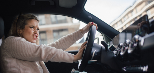 Upset woman driving her car in city.