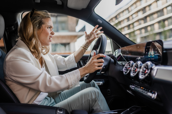 Upset woman driving her car in city.