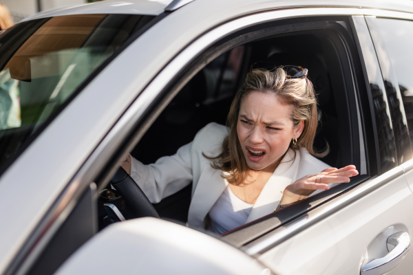 Upset woman driving her car in city.