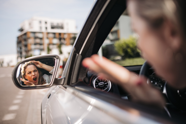 Nervous woman driving her car in a city, shoutng at somebody.