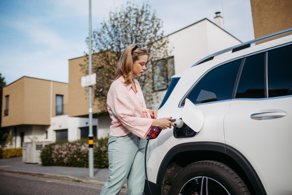 Woman charging the electric car, sustainable and economic transportation concept.