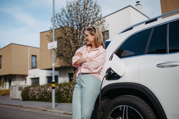 Young woman charging electric car in home, sustainable and economic transportation concept.