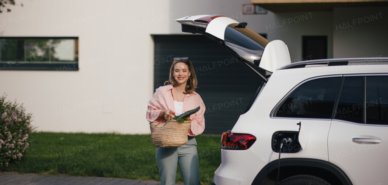 Woman coming back from a grocery store, waiting for car charging.