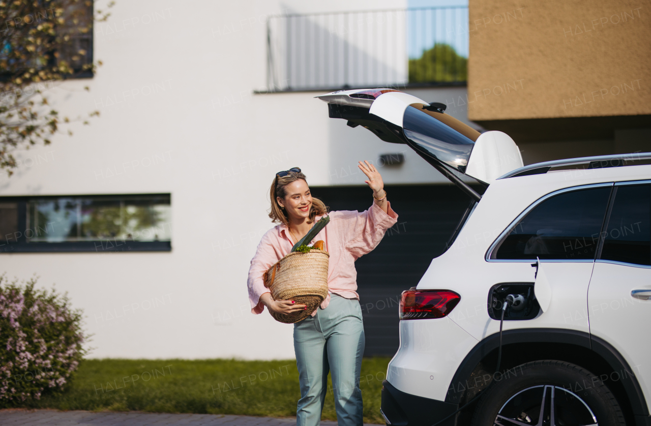 Woman coming back from a grocery store, waiting for car charging.