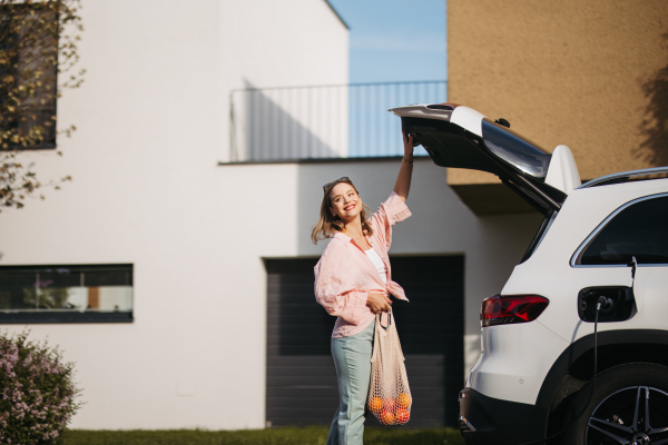 Woman coming back from a grocery store, waiting for car charging.