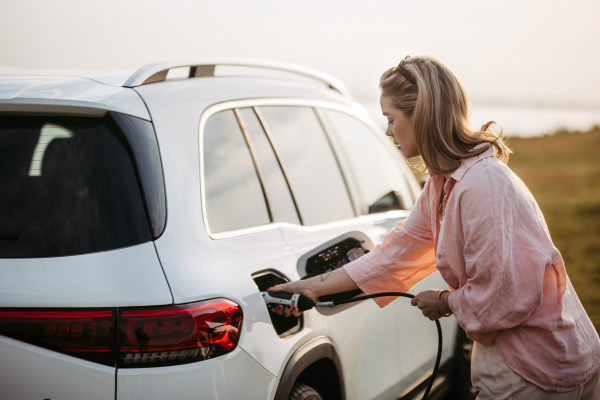 Woman charging the electric car, sustainable and economic transportation concept.