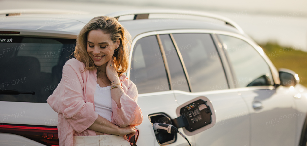 Woman charging the electric car, prepared for charging it, sustainable and economic transportation concept.