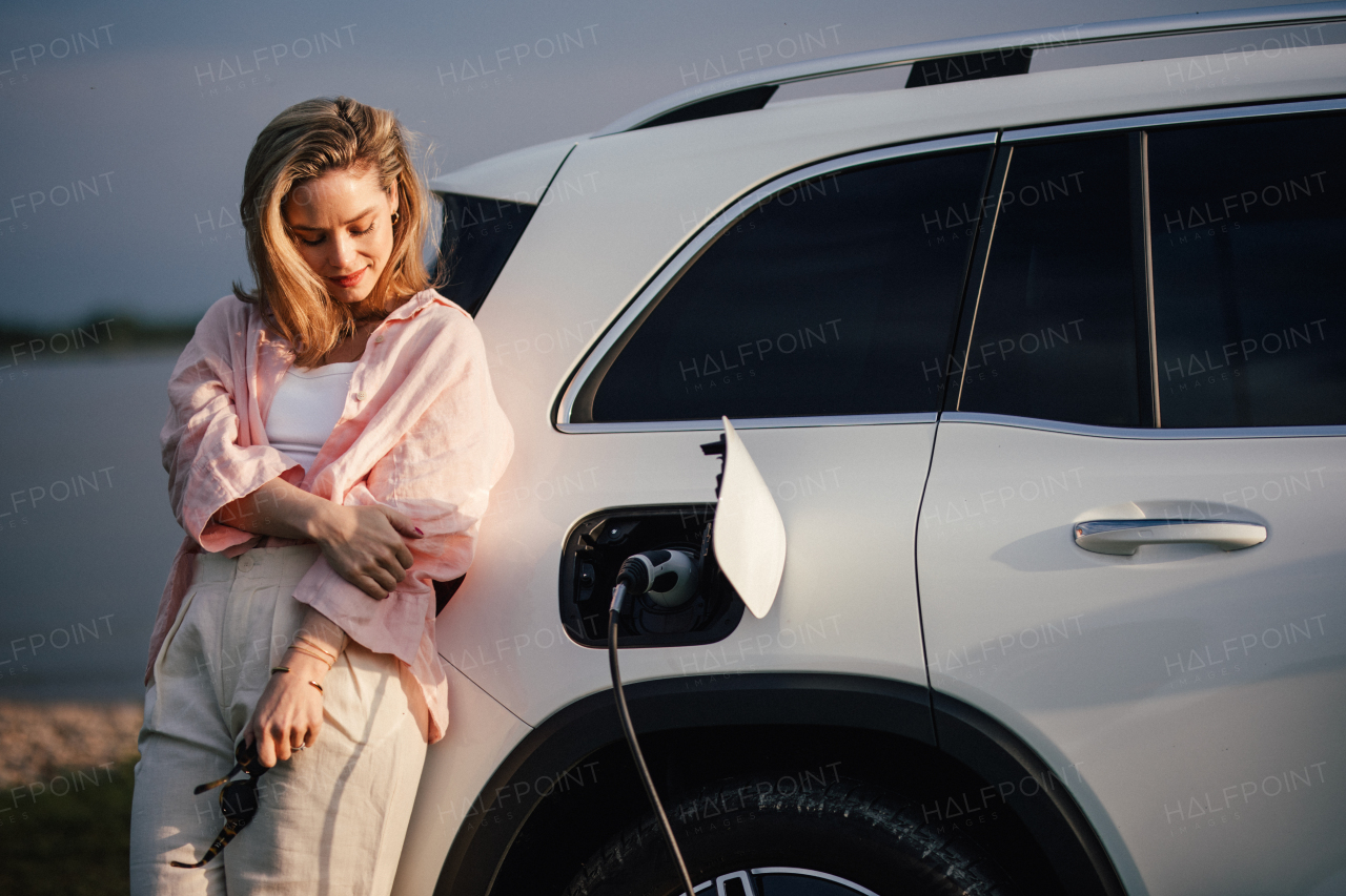 Young woman charging electric car in home, sustainable and economic transportation concept.