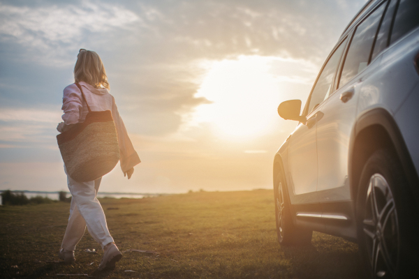 Young woman going out of car, walking in the nature.