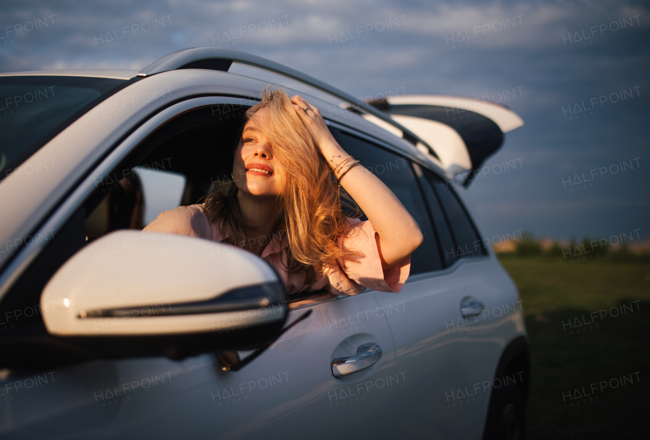 Happy woman driving her new electric car in a city.