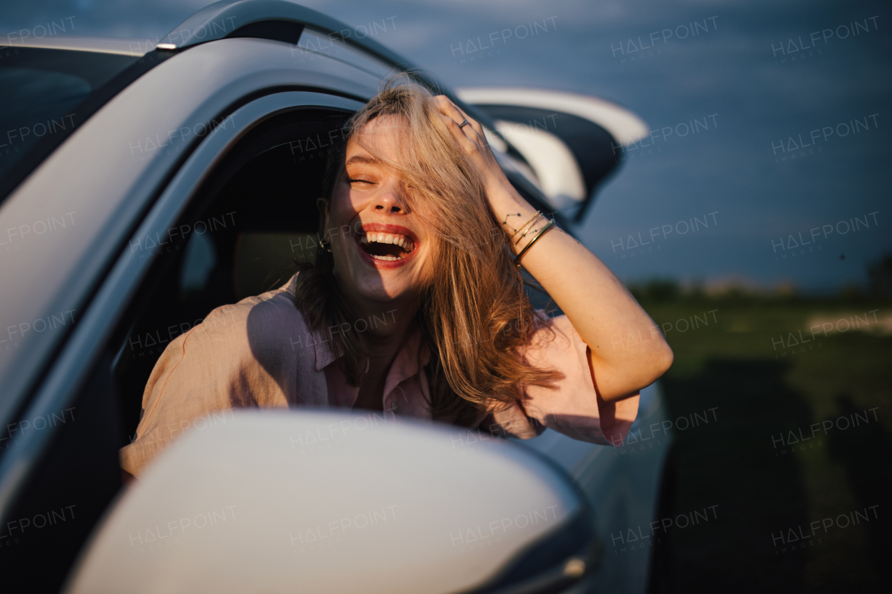 Happy woman driving her new electric car in a city.