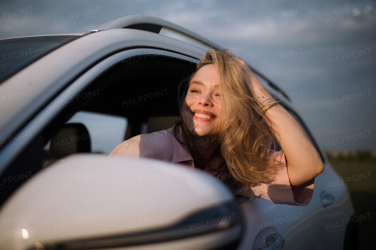 Happy woman driving her new electric car in a city.