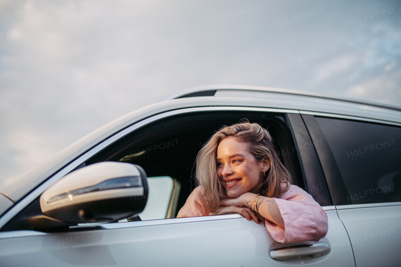 Happy woman driving her new electric car in a city.