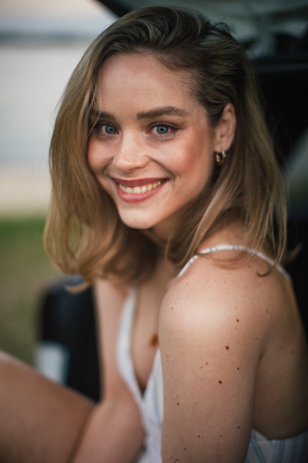 Portrait of beautiful woman sitting in car trunk.