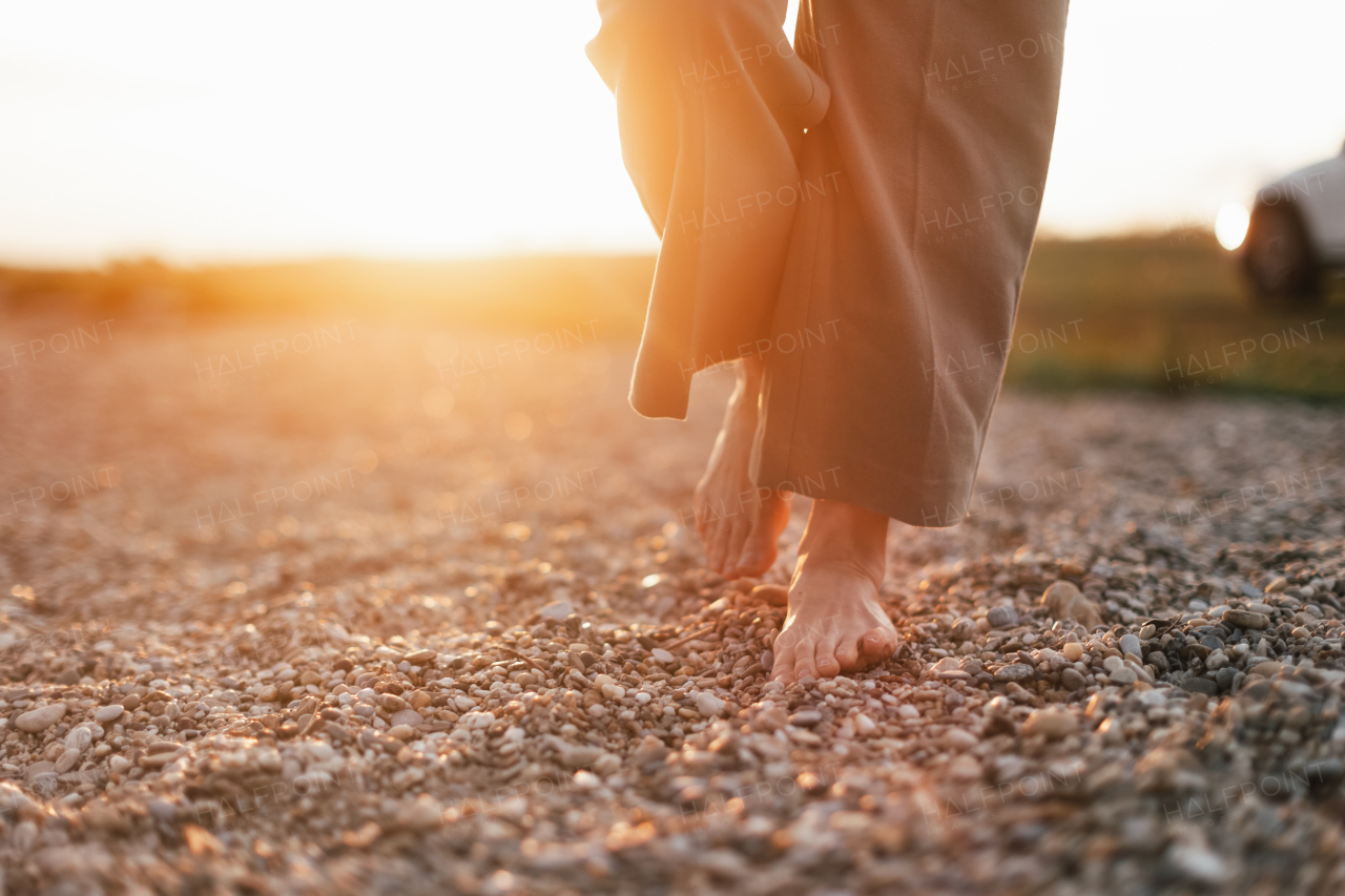 Close up of womans barefoot feet walking on a rock beach.