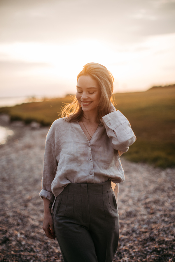 Young woman walking near the lake, enjoying summer time.