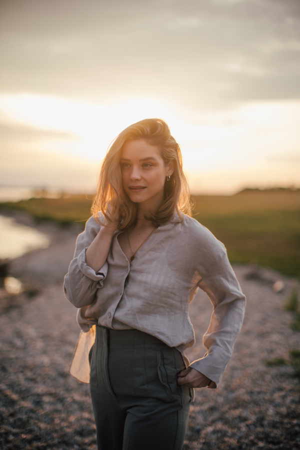 Young woman walking near the lake, enjoying summer time.