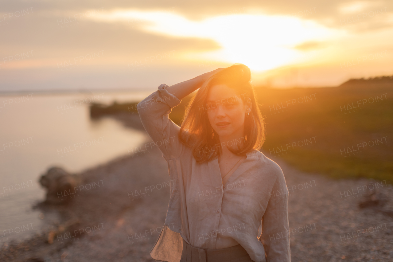 Young woman walking near the lake, enjoying summer time.