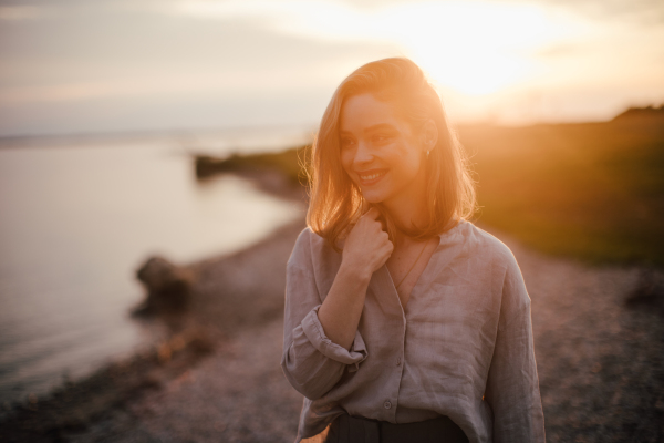 Young woman walking near the lake, enjoying summer time.