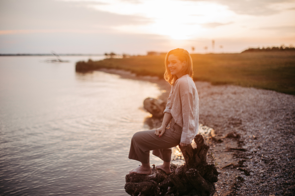 Young woman resting near the lake, enjoying summer time.