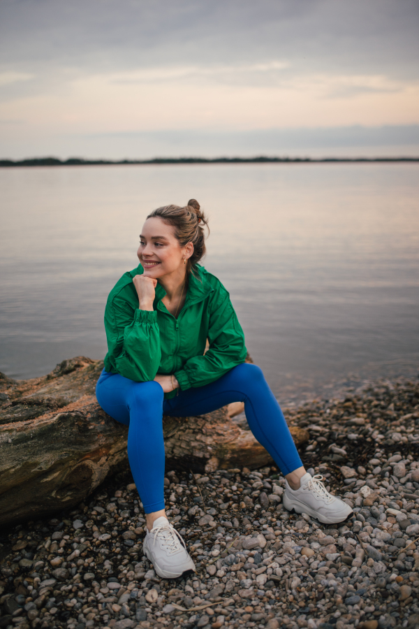 Portrait of happy woman in sportive clothes resting near a lake.