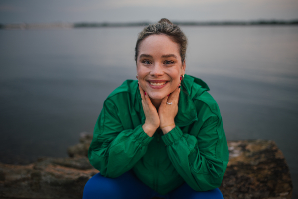 Portrait of happy woman in sportive clothes resting near a lake.