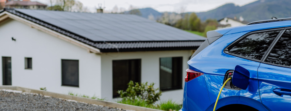 Close-up of electric car charging near a family house.