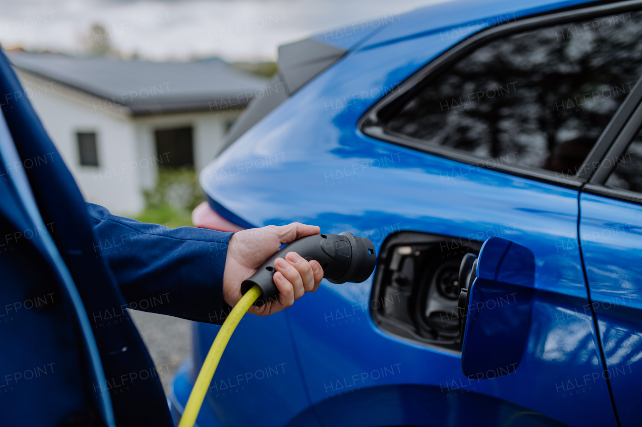 Close-up of electric car charging near a family house.