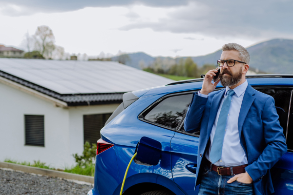 Mature businessman waiting for charging his new electric car.