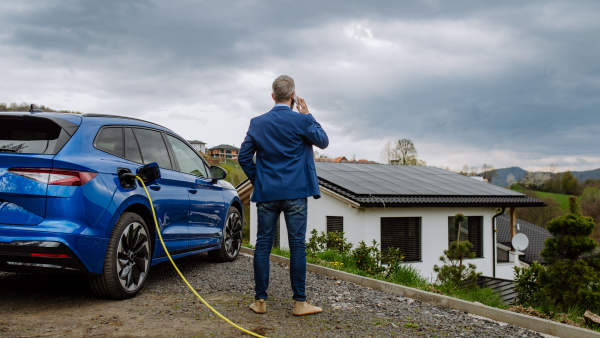 Mature businessman waiting for charging his new electric car.