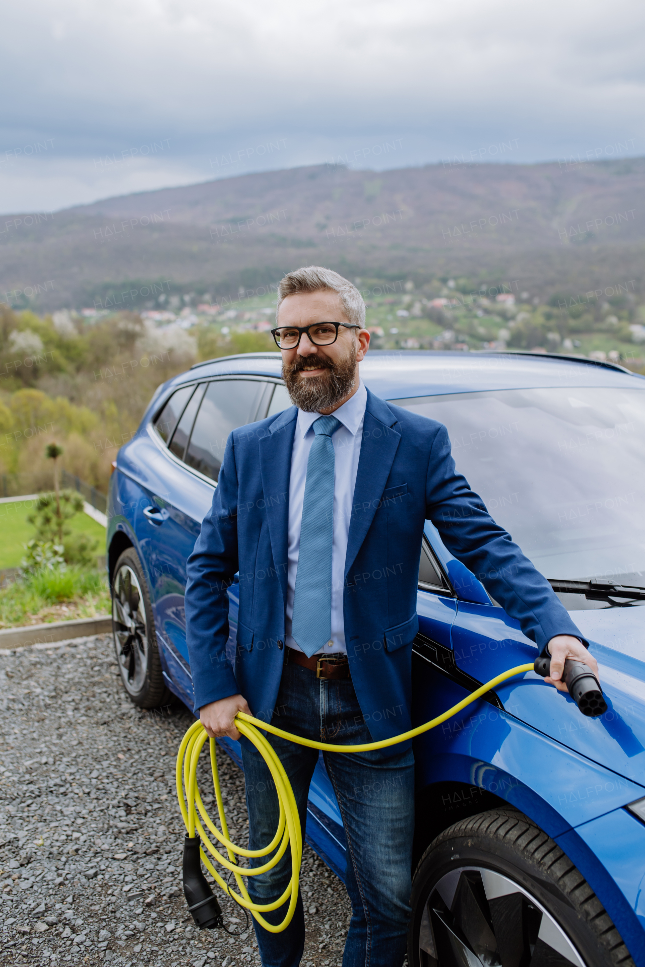 Close up of businessman holding power supply cable from his new electric car.