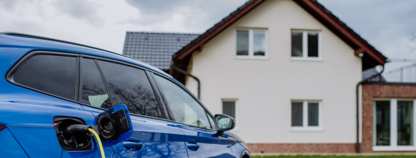 Close-up of electric car charging near a family house.