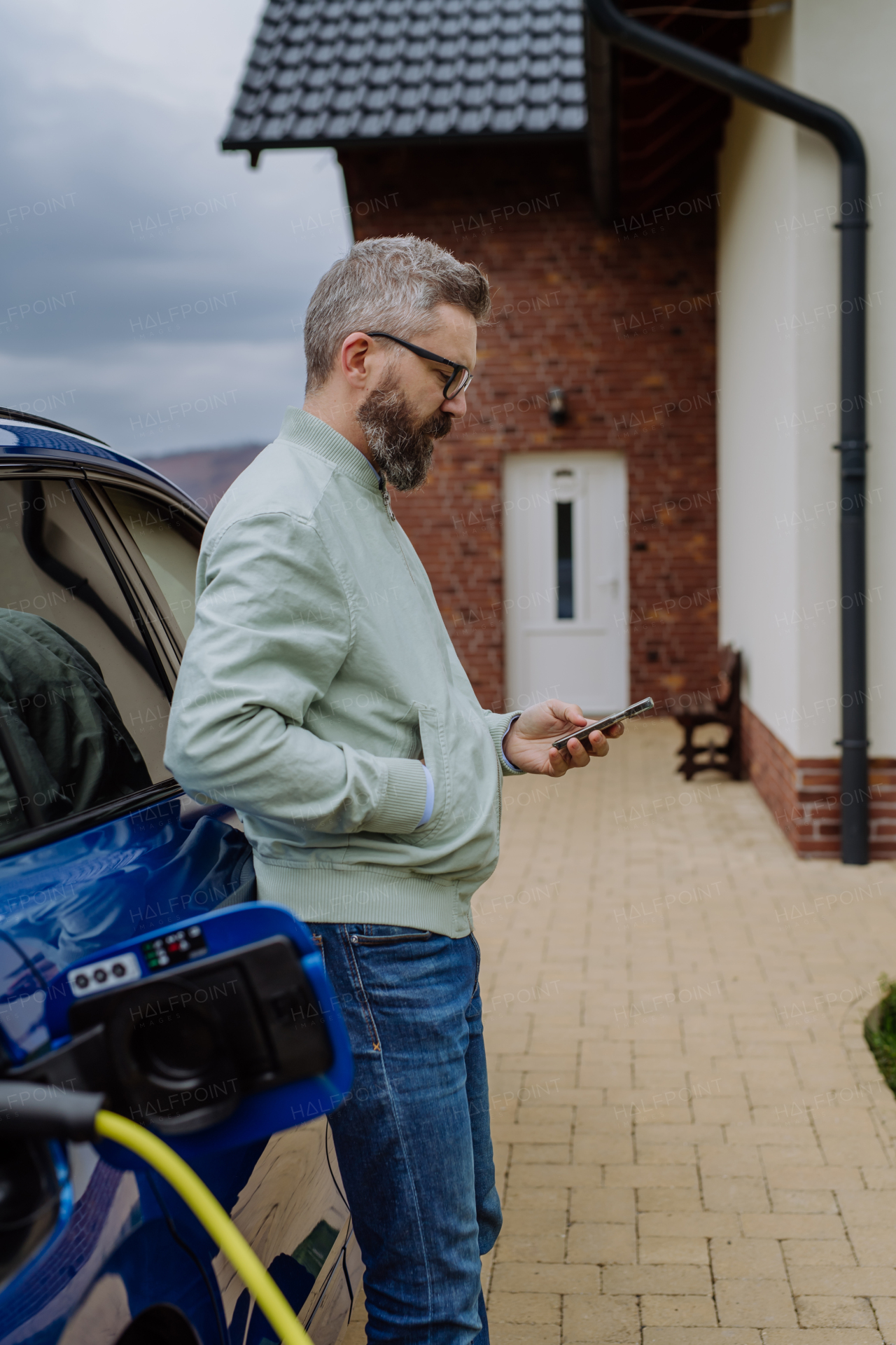 Mature man waiting for charging his new electric car.